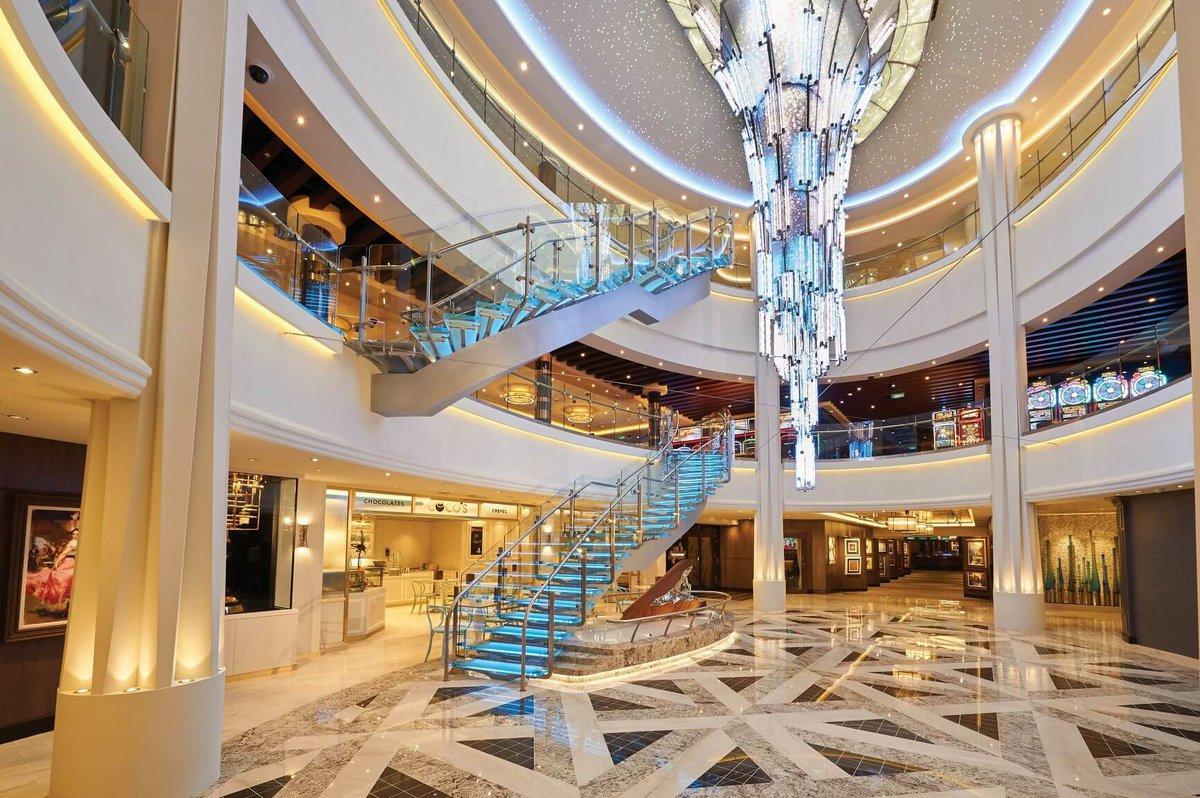 Elegant cruise ship atrium with a grand illuminated glass staircase and crystal chandelier